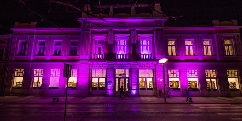 Pročelje Gradske knjižnice Požega osvijetljeno ljubičastom bojom 
